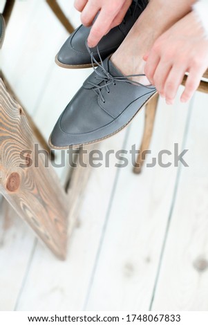 gray stylish and modern women's loafers on a layout, in the hands of a girl, shoes on toes, trendy photos of shoes