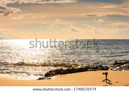 Camera on little tripod taking film video or shooting images pictures of sea coastline in Greece Peloponnese