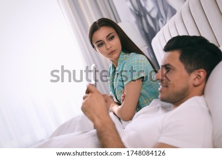Man preferring smartphone over spending time with his girlfriend at home. Jealousy in relationship Royalty-Free Stock Photo #1748084126