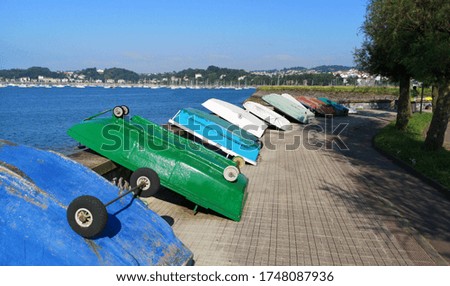 A picture of a sea promenade with many boats turned upside down on a sunny day