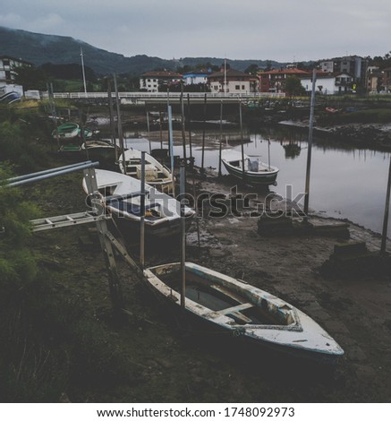 A picture of boats on the mud with a cityscape on the background