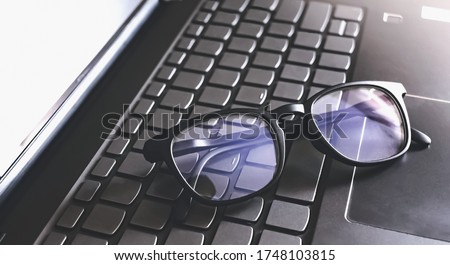 blue light blocking glasses on the keyboard button of computer laptop. working or learning online. Royalty-Free Stock Photo #1748103815