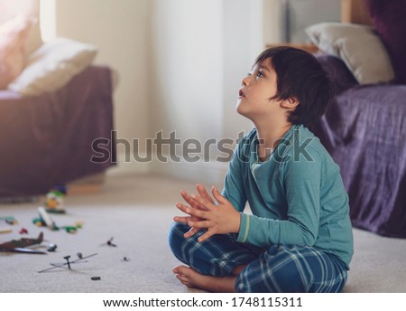 Happy kid sitting on floor clapping hands while watching cartoon on TV in living room, Cheerful child boy wearing pyjama sitting on carpet relaxing at home on weekend, Healthy and Positive kid concept