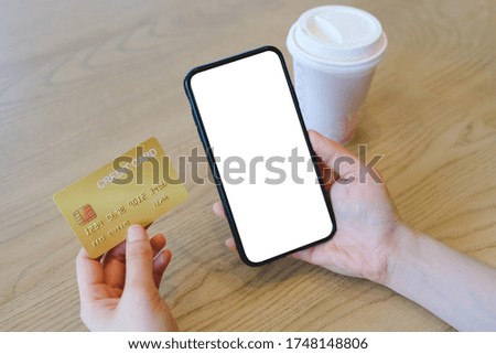 Mockup image of a hands holding credit card and a black mobile phone at cafe.