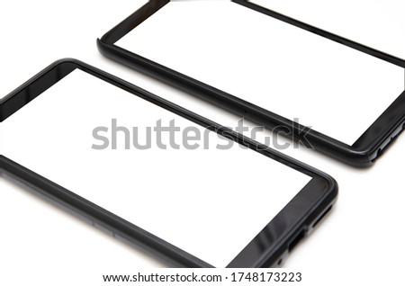 Two smartphones of black color with a white screen lie on a white background nearby, deviated from each other, top view and bottom from an angle in macro