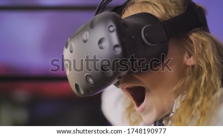A teenage girl plays a virtual game in black virtual reality glasses.