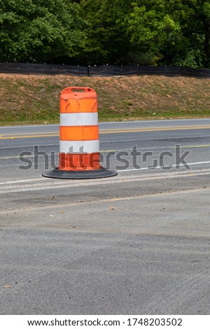 Single traffic barrel dividing an asphalt roadway, traffic safety creative copy space, vertical aspect