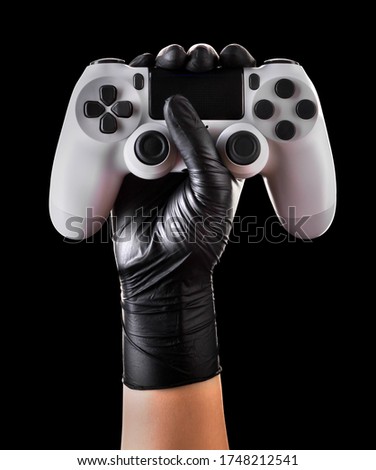 Hand in black gloves holding console gamepad isolated on black background with clipping path. Concept of medical and healthcare in video game industry