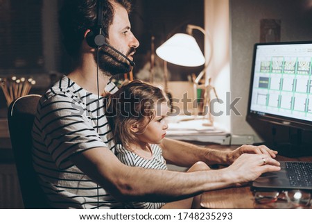 Father and daughter are working on a laptop. businessman working from home and watching the child. A young man works on a computer. Launch. Freelancer concept. Family on quarantine Royalty-Free Stock Photo #1748235293
