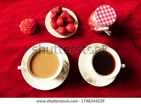 White and black coffee on a velvet table. cloth. Candle, strawberries, jar around. 