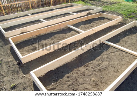 Wooden formwork from new boards for vegetable beds in the garden, preparation and construction, carpentry. Royalty-Free Stock Photo #1748258687