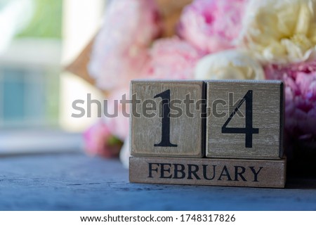 14 February wooden cubes calendar, flowers on the background.