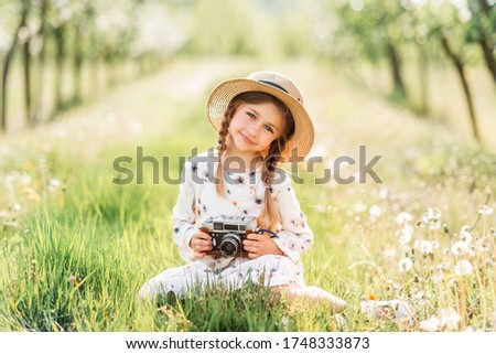Summer photo with a little girl. A child with a camera in nature.