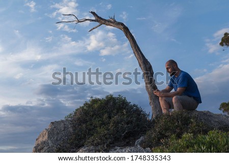 Summer wanderlust concept image of  a man with his mobile enjoy and resting on the top of a cliff in Mallorca Sant Elm Village