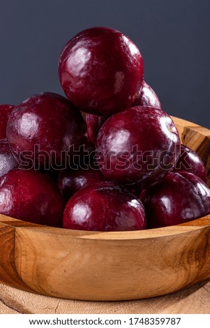 
Some plums in a basket with jute fabric. Wood background