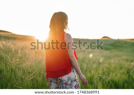 Portrait of a beautiful young woman in red dress posing outdoors at sunset. High quality photo