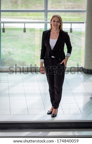 Businesswoman standing in a modern Building with a white shirt and black pants