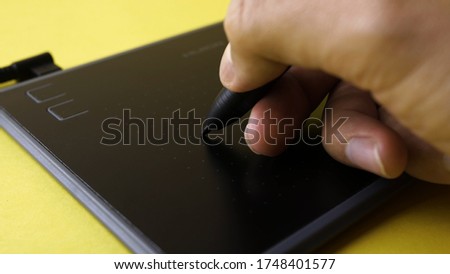 Closeup of the designer draws on the graphic tablet on the computer.