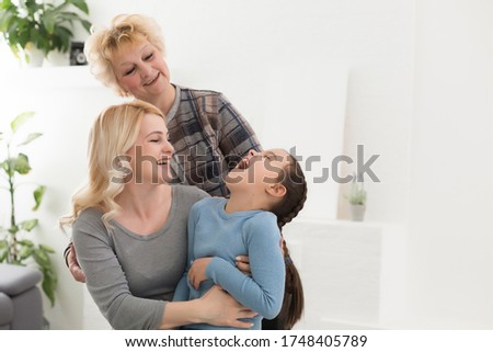 Portrait of three generations of women look at camera posing for family picture, cute little girl hug mom and granny enjoy time at home, smiling mother, daughter and grandmother spend weekend together