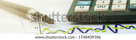stylish fountain pen with quill lies near outdated digital calculator edge on paper with graph extreme closeup