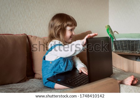 Beautiful little girl sitting on couch in living room and using laptop computer.Online training, games and watching cartoons. New generation. bright room