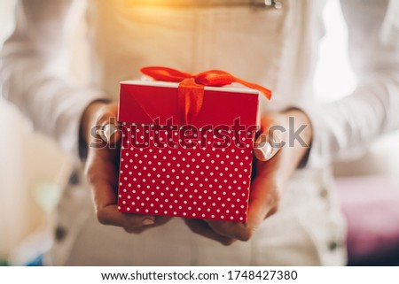 Young woman hands holding red gift box
