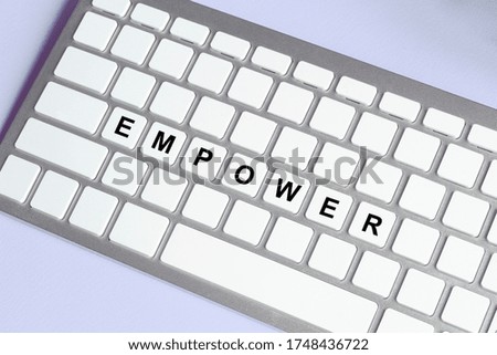 detail of white keyboard with the word EMPOWER on the space bar. concept of smart working