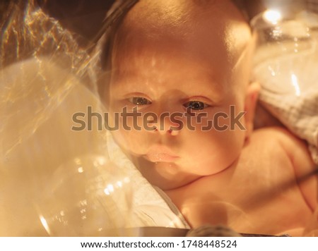 Portrait of a beautiful baby with blue eyes and brown hair, golden warm light