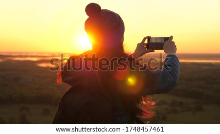 Healthy cheerful woman travels at dawn and photography nature on phone. free Young girl tourist blogger records selfie video on top of the mountains using a smartphone with a beautiful landscape.