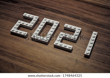 Diagonal Numerals 2021 made of white toy plastic bricks. New year concept. Vision of new twenty twenty logo. Wood Grain background. Poster, banner or modern and creative greeting card