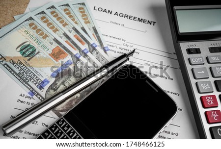 loan agreement with calculator and money on desk.