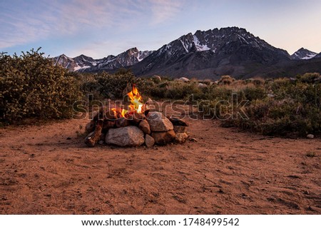 desert campfire in stone fire pit at base of mountains under sunset sky Royalty-Free Stock Photo #1748499542