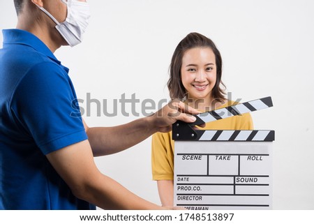 worker man wear 
face mask and  holding clapper board for making video cinema in studio. Movie production clapper board or slate film concept.
