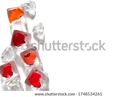 Creative image of red and orange lipstick samples. Lipstick strokes on artificial ice cubes isolated on white background. Cooling cosmetic products arranged in random order. Summer makeup concept.
