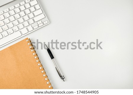 White office desk table. Workspace with keyboard, notebook, pen on white background. Top view with copy space, flat lay.