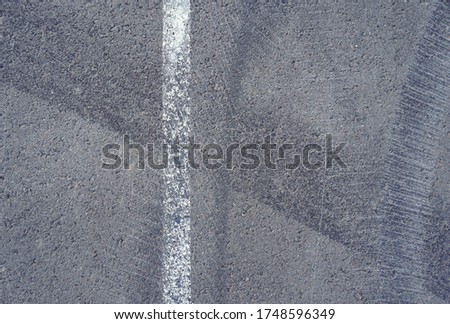 Asphalt texture with white line and tire marks.  Smooth asphalt road. Tarmac dark grey grainy road background.Top view Royalty-Free Stock Photo #1748596349