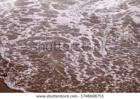 sand and wave on the sea shore. sand, waves and foam as wallpaper design. holiday concept.