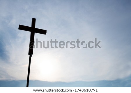 A christian cross under cloudy sky.
