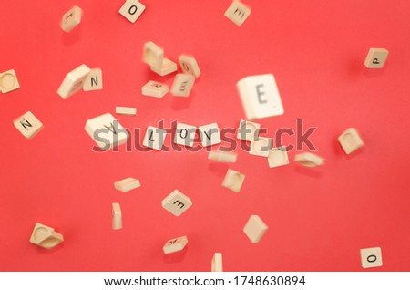 red background with scrabble pieces with the word love and pieces falling Royalty-Free Stock Photo #1748630894