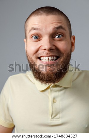 Close-up portrait of a young happy man in a yellow T-shirt, emotions on a gray background. isolated.