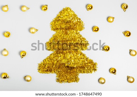  Golden Christmas tree made from tinsel and pattern of golden Christmas balls on a gray background. New Year or Christmas concept. flat lay