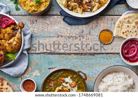Indian cuisine dinner: tandoori chicken marinated in tikka, biryani, red lentil curry dal with rice naan, palak paneer and basmati rice on wooden background with copy space