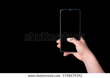 female hand holding a phone with black screen, mockup concept, isolated on black background