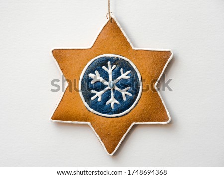 Christmas star-shaped gingerbread decorated with colored icing on a white background, hand-made and decorated gingerbread, blue frosting on a gingerbread, gingerbread on a Christmas tree 