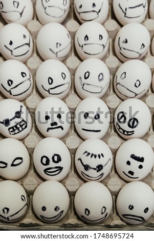 White eggs with faces drawn arranged in carton. emoticons drawn with a black marker. angry, happy, neutral and another smile background of masked eggs. top view