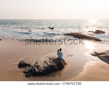 Scenic aerial view of happy romantic couple on the beach sit on th stone and look at each other. wedding by the sea Royalty-Free Stock Photo #1748701700