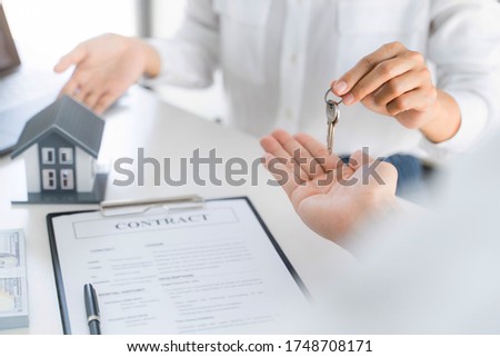 Real estate agent broker give a key with house sign contract.