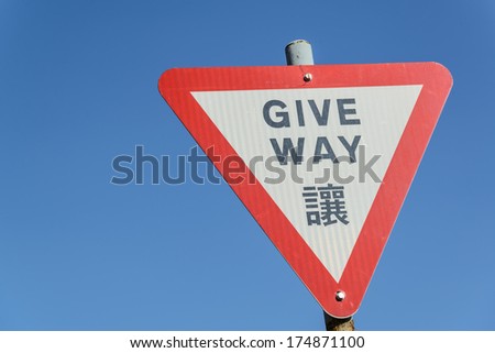 Give way sign with traditional Chinese translation on blue sky