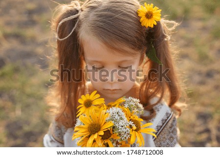 little girl with yellow flowers in the field