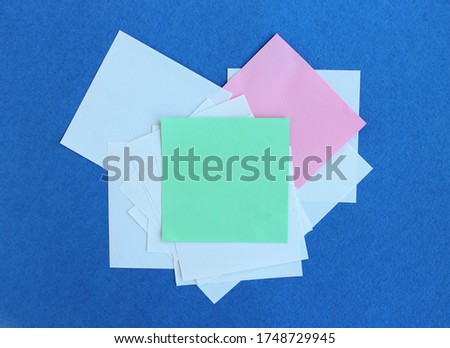 White, green and pink sheets of writing paper on a blue background. All for work records.